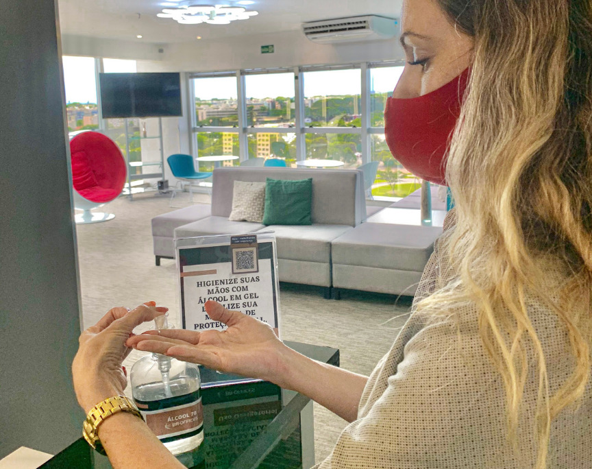 pessoa colocando alcool em gel nas maão no espçao de coworking do BR.Offices